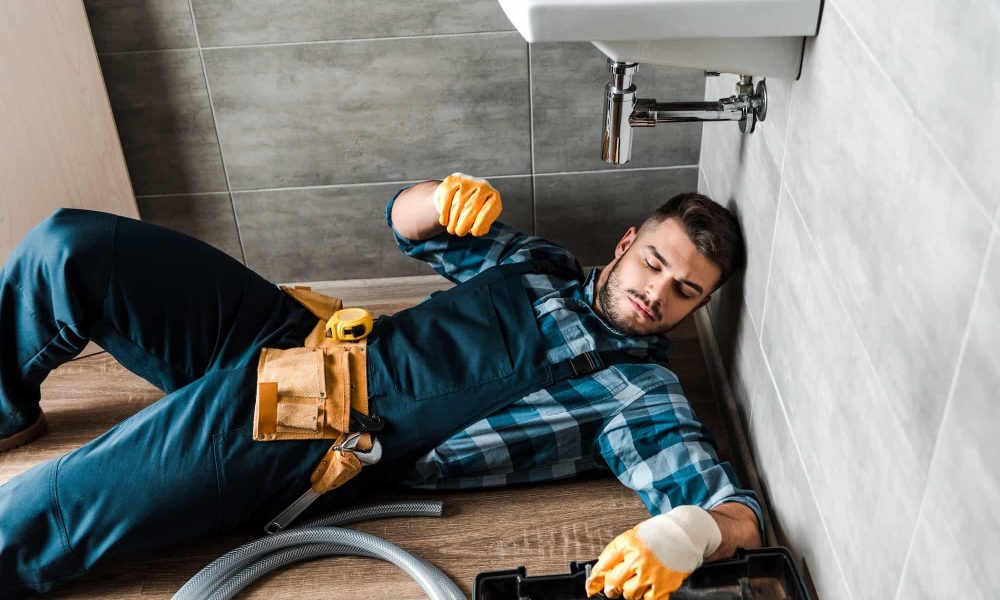 bearded-handyman-lying-on-floor-near-toolbox-in-bathroom.jpg